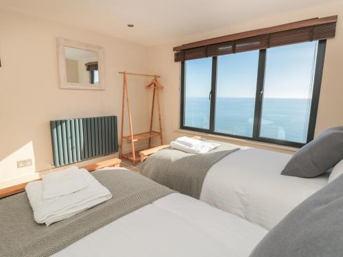 two beds in a room with a large window at The Gulls in Dartmouth