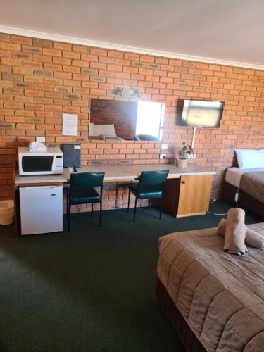 a hotel room with a bed and a desk with chairs at Regency Court Motel in Cobram