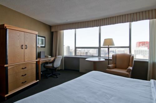 a hotel room with a bed and a desk and window at Chateau Lacombe Hotel in Edmonton