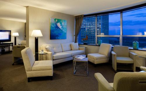 a living room with a couch and chairs and a tv at Chateau Lacombe Hotel in Edmonton