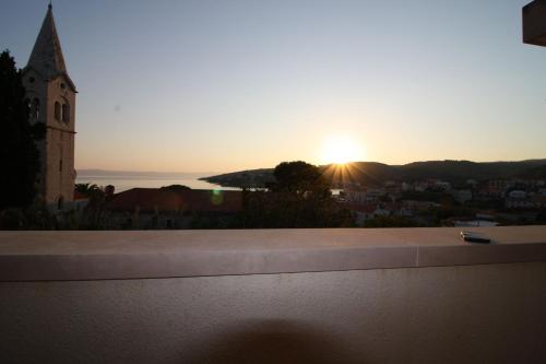 a sunset from the roof of a building with a church at Apartment and Room Lada in Sumartin