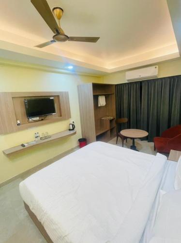 a bedroom with a white bed with a ceiling fan at Royal Beach International in Puri