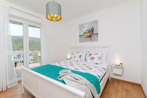 a white bedroom with a bed and a window at Apartment Ivona in Tribalj
