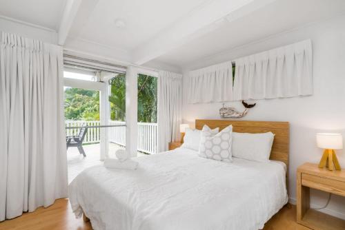 Habitación blanca con cama y balcón. en Lower Decks, en Byron Bay