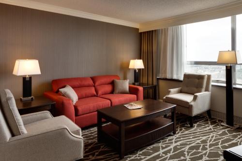 a living room with a red couch and two chairs at Chateau Lacombe Hotel in Edmonton