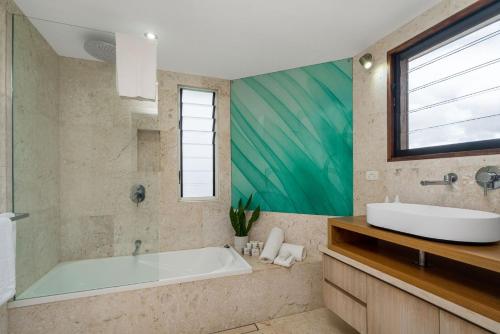 a bathroom with a tub and a sink and a window at Belongil Beach House in Byron Bay