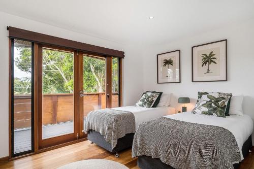 a bedroom with two beds and a large window at Belongil Beach House in Byron Bay