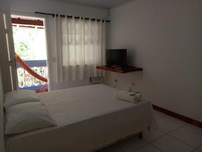 a bedroom with a white bed and a window at Casa Brasil pousada e lazer in Trindade