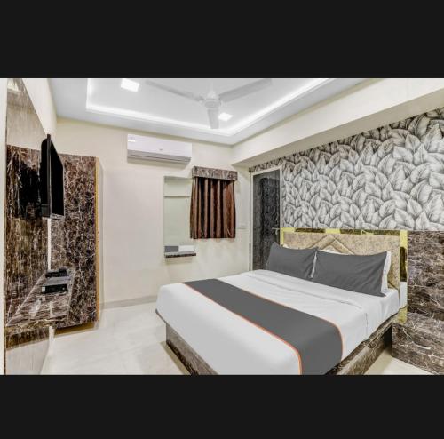 Hotel Bhavya Residency في Jāmb: غرفة نوم بسرير كبير وجدار حجري