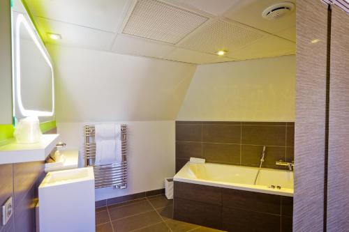 a bathroom with a tub and a sink at Hôtel et Spa La Villa K - Basel Airport in Saint-Louis