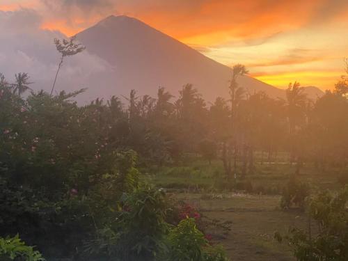 a mountain in the distance with trees and a sunset at BALI AMED FEEL HOME VILLA in Amed