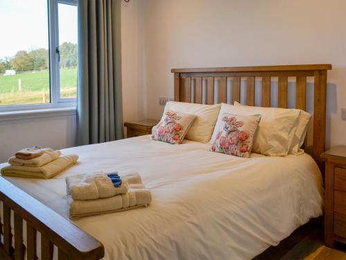 a bedroom with a bed with towels and a window at Inverallan in Amisfield Town