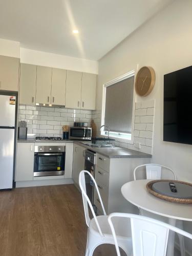 a kitchen with white appliances and a table with chairs at Bundalong Villas in Bundalong