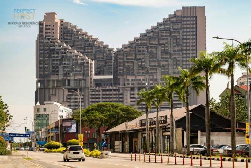 a large building with palm trees in front of a street at Imperio Residence Seafront by Perfect Host in Melaka