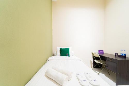 a bedroom with a bed with a desk and a green wall at Singgahsini Near MRT Haji Nawi in Jakarta