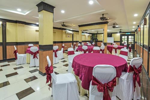 un salón de banquetes con mesa y sillas con arcos rojos y blancos en Super OYO Capital O 90656 Sera Sentosa Inn 