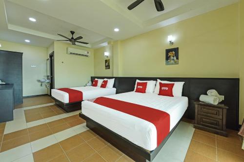 a bedroom with two beds with red and white pillows at Super OYO Capital O 90656 Sera Sentosa Inn 