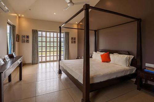 a bedroom with a canopy bed and a desk at StayVista's Shivom Villa 12 - A Serene Escape with Views of the Valley and Lake in Lonavala