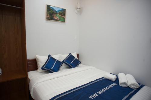 a bedroom with a bed with blue and white pillows at The White House in Ho Chi Minh City