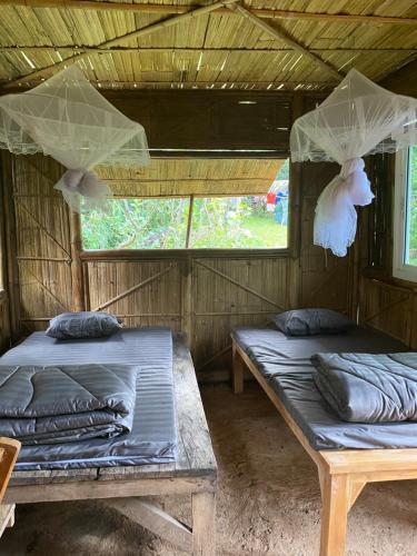 two beds in the inside of a room at Khaokhopimphupha farmstay เขาค้อพิมภูผาฟาร์มสเตย์ ไม่มีไฟฟ้า น้ำจากน้ำตกธรรมชาติ Low cabon with Sustainability cares in Ban Non Na Yao