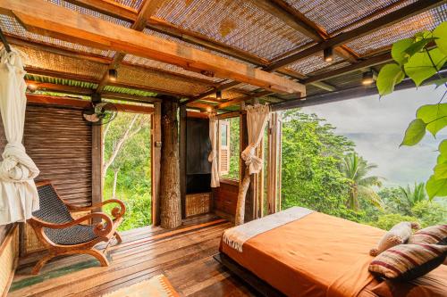 a bedroom with a bed and a large window at Bird Hills Bamboo House in Karangasem