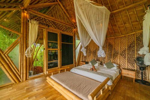 een slaapkamer met een bed in een kamer met ramen bij Bird Hills Bamboo House in Karangasem