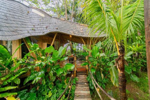 un camino de madera a través de una selva con un puente de madera en Bird Hills Bamboo House, en Karangasem