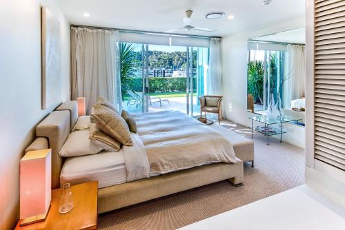 um quarto com uma cama grande e uma janela grande em Pavillions 1 - NEW Waterside Luxury with pool em Hamilton Island