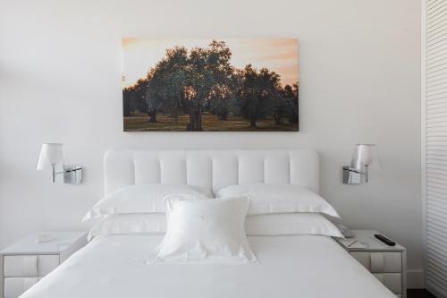 a bedroom with a white bed with a painting on the wall at Magna Pars l'Hotel à Parfum, Small Luxury Hotels of the World in Milan