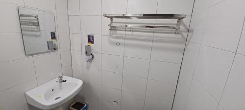 a white bathroom with a sink and a mirror at SY Staycation - Studio in Bayan Lepas