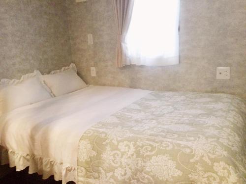 a bedroom with a white bed with a window at アパートメントホテル Mimoza in Sumoto