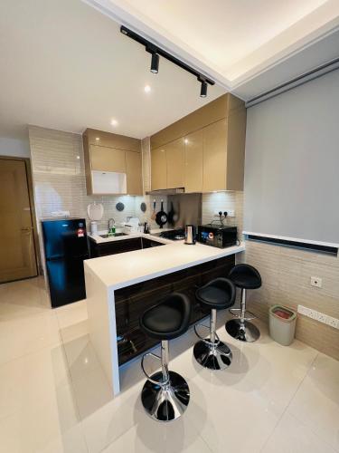 a kitchen with two bar stools and a black refrigerator at R&F PRINCESS COVE at ANJU in Johor Bahru