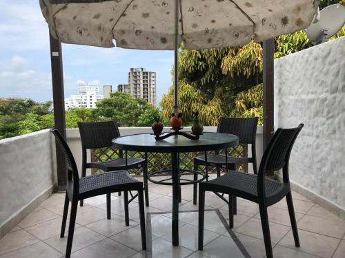 a table and chairs on a balcony with an umbrella at Vacaciones Playa Club Casa Blanca Same Esmeraldas in Same