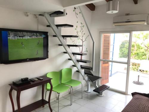 a living room with a staircase with a television and green chairs at Vacaciones Playa Club Casa Blanca Same Esmeraldas in Same