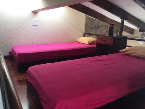 two beds in a room with pink sheets at Vacaciones Playa Club Casa Blanca Same Esmeraldas in Same
