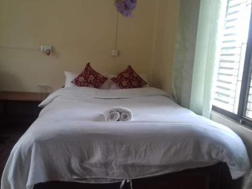 a bedroom with a white bed with two towels on it at Crocodile Safari Camp in Chitwan