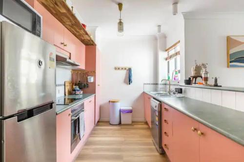 a kitchen with pink and white walls and wooden floors at Midnights in Morocco in Brisbane