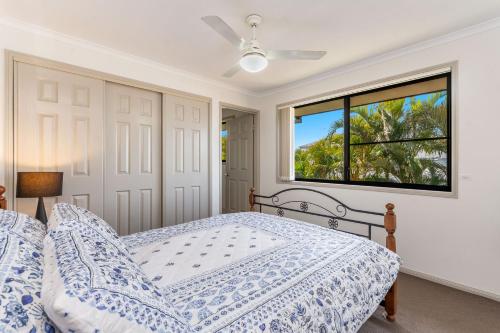 a white bedroom with a bed and a window at Amarillo in Yamba