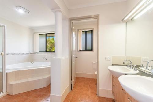 a white bathroom with two sinks and a tub and a shower at Amarillo in Yamba