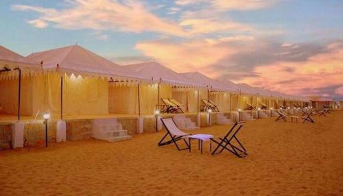 a row of tents in the desert with tables and chairs at Marina Dessert Camp in Sām
