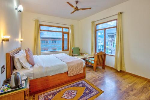 Ayushman Hotels في مانالي: غرفة نوم بسرير ومكتب ونافذة