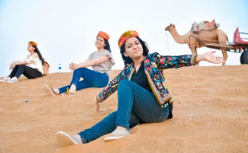 a group of women sitting on the sand with a camel at Marina Dessert Camp in Sām