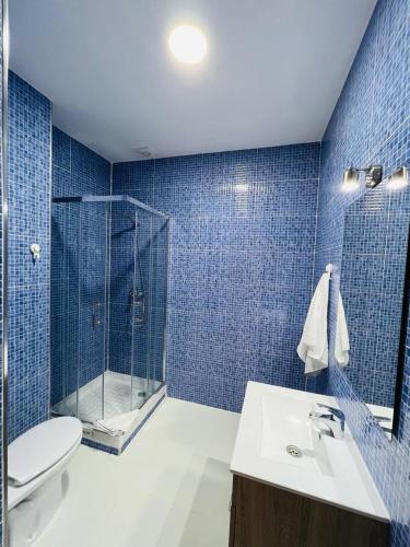 y baño de azulejos azules con ducha y lavamanos. en HOSPEDAJE COLONIA VALLECAS, en Madrid