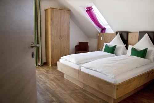 a bedroom with a bed with white sheets and green pillows at Pension Sperlhof in Erding