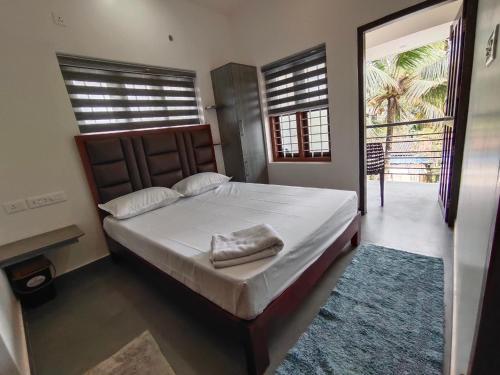 a bedroom with a large bed with a large window at Dune Homestay in Alleppey