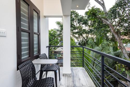 a balcony with a table and chairs and trees at Dune Homestay in Alleppey