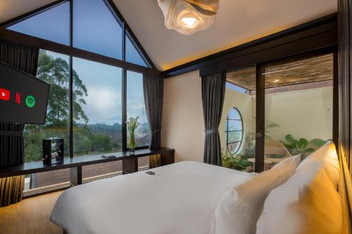 ein Schlafzimmer mit einem Bett und einem großen Fenster in der Unterkunft Sunsetfalls Gardens and Resort in Magelang