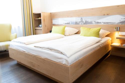 a large bed with white sheets and green pillows at Villa Benz Hotel garni in Schwetzingen