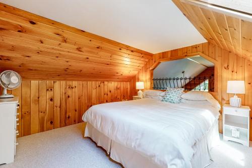 a bedroom with a large white bed in a room with wooden walls at Marwood Lake Cottage in Wakefield