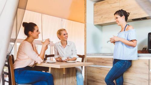 a group of three women sitting at a table at Glamping Olimia Adria village in Podčetrtek